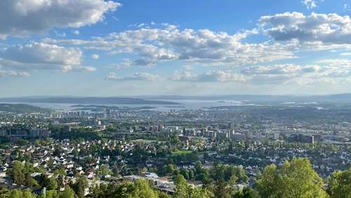 Utsikt mot Oslofjorden med by og skog, sol, blå himmel