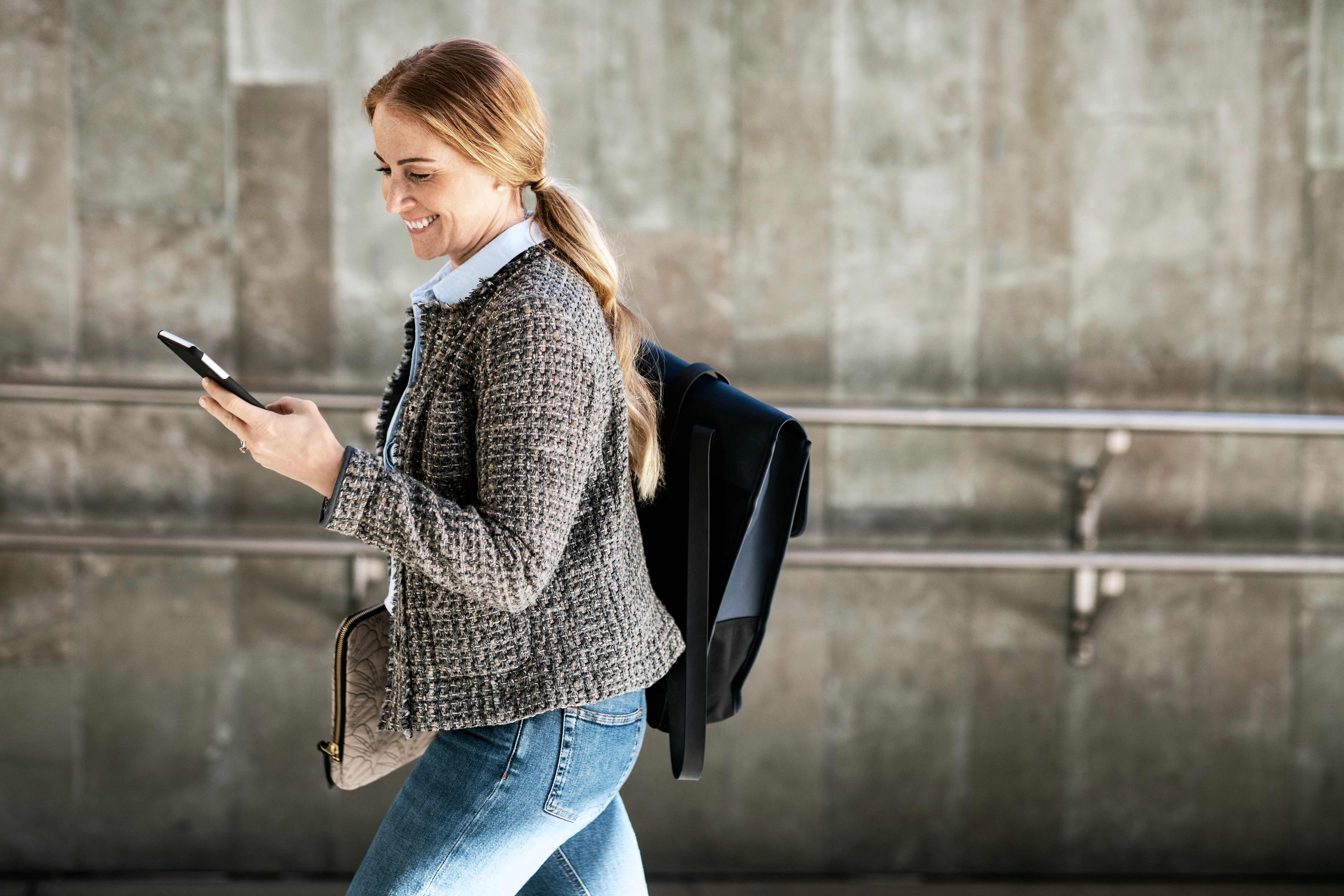Kvinne går på plattformen med mobil i hånda