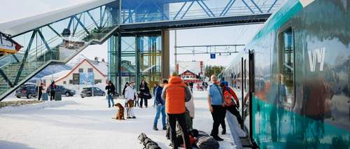 toget står på Geilo stasjon og folk går inn og ut med utstyr og bagasje