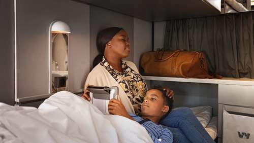 Kvinne sitter i sengen i en sovekupé i toget på Bergensbanen, med sønnen sin liggende på fanget mens han ser på en iPad.