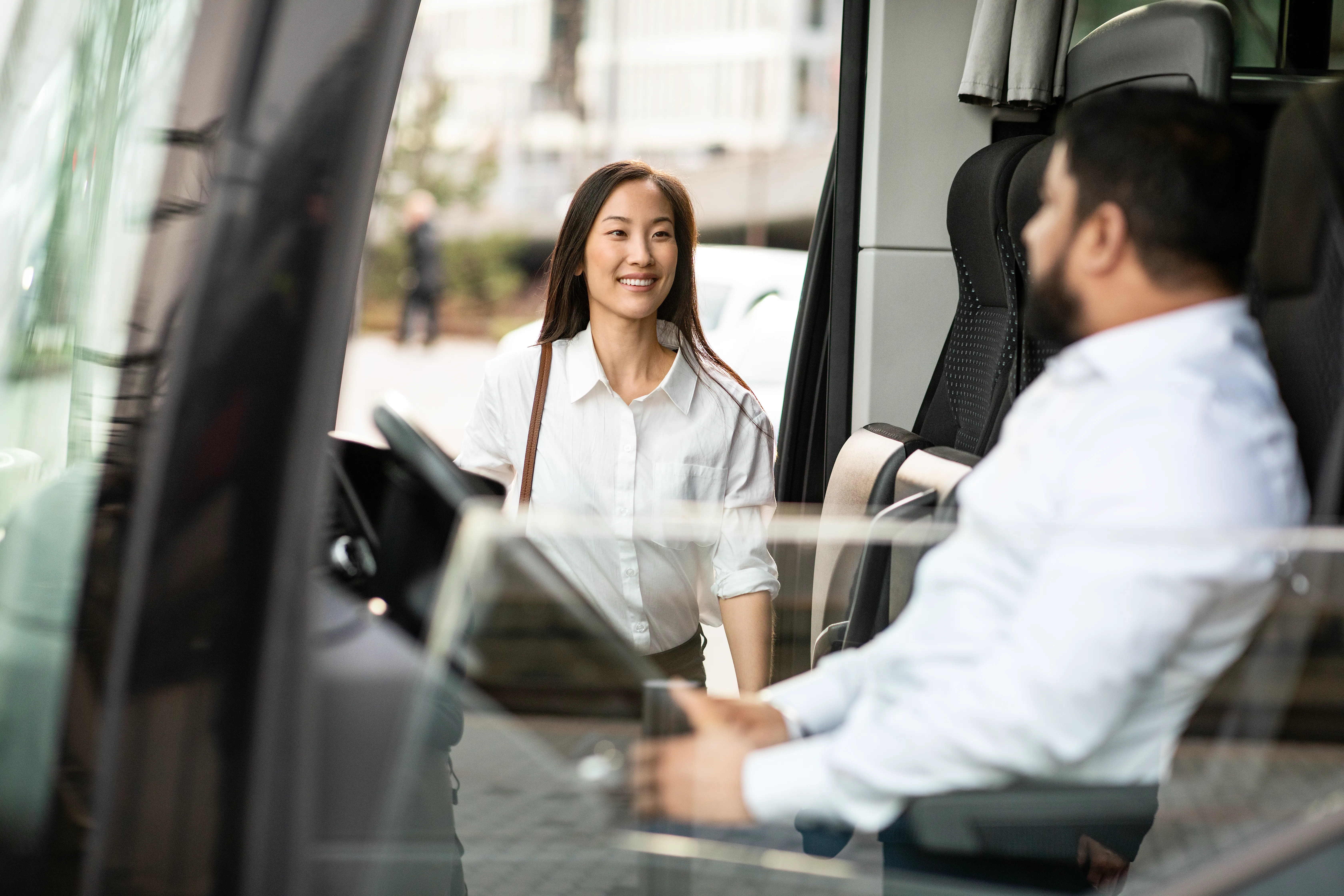 Kvinnelig passager stiger ombord på bussen og smiler til sjåføren