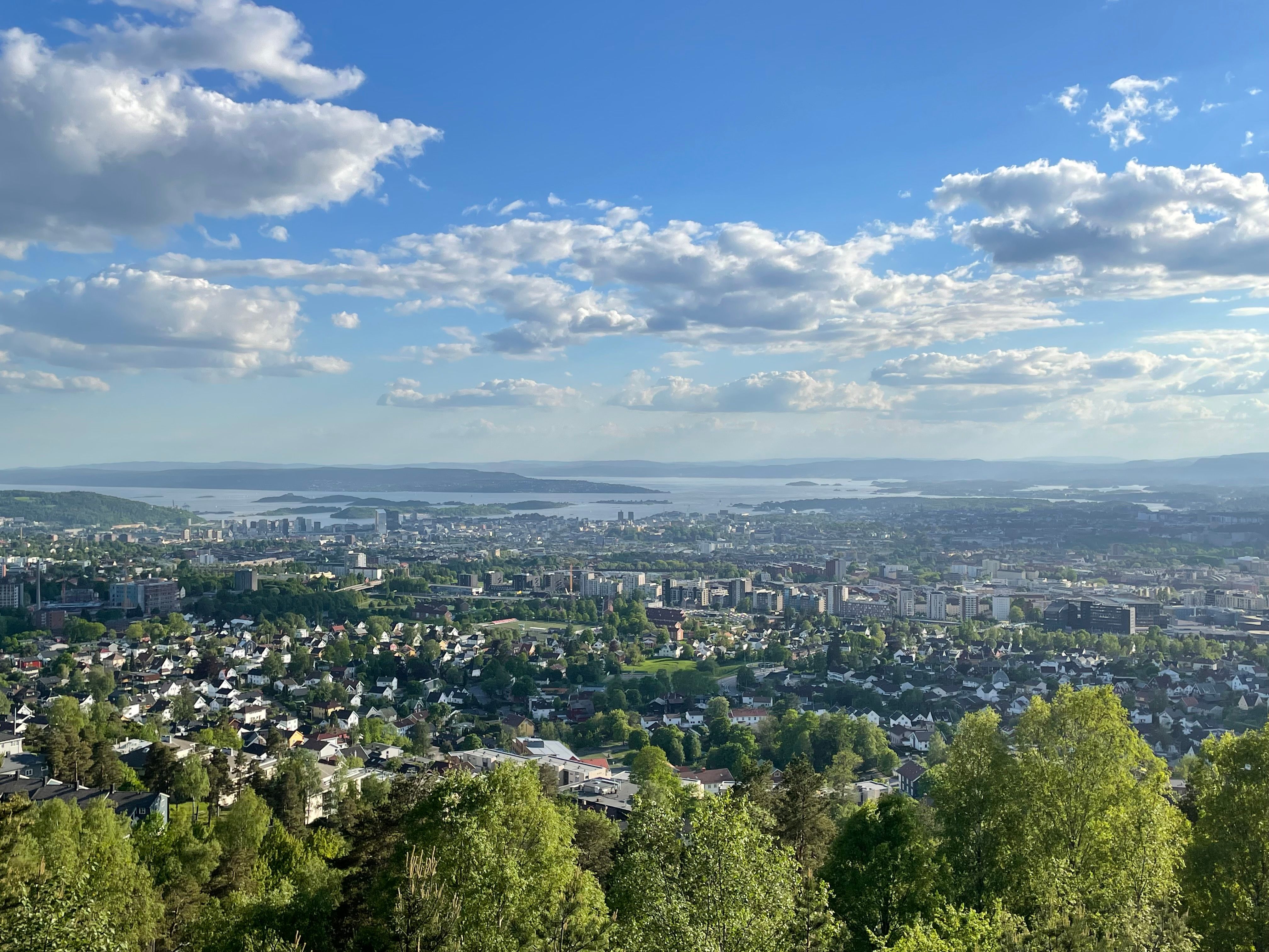 Utsikt mot Oslofjorden med by og skog, sol, blå himmel