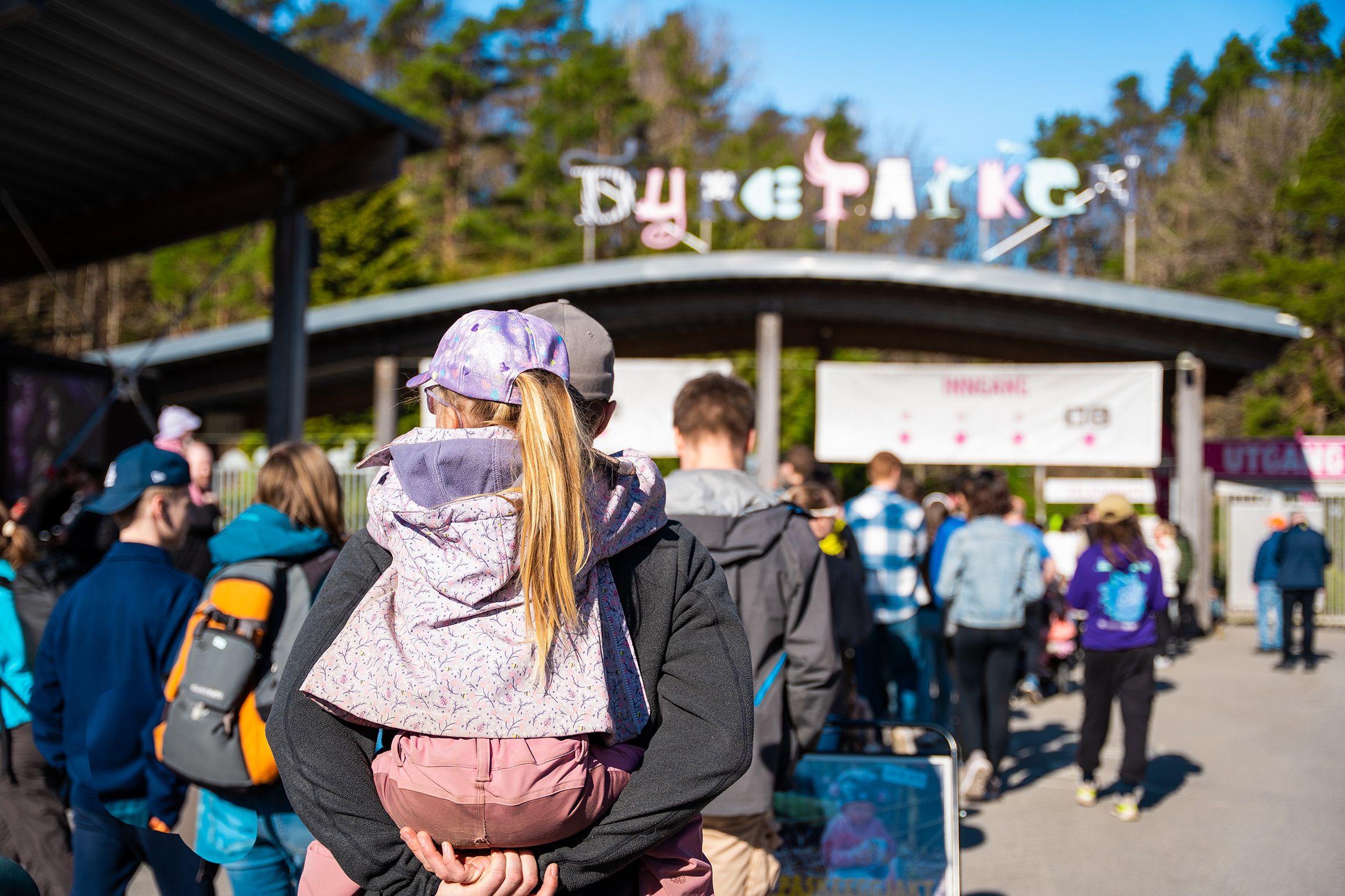 Et barn som blir bært på ryggen av en voksen på vei inn i Kristiansand Dyrepark.