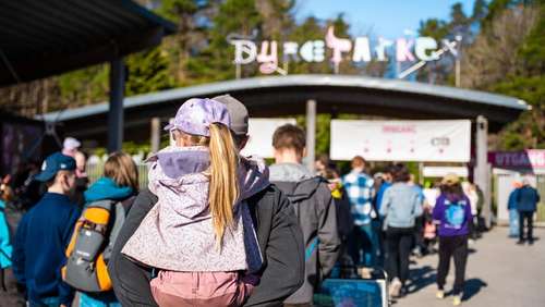 Et barn som blir bært på ryggen av en voksen på vei inn i Kristiansand Dyrepark.