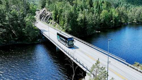 En dobbeldekker fra Vy parkert langs fjorden.