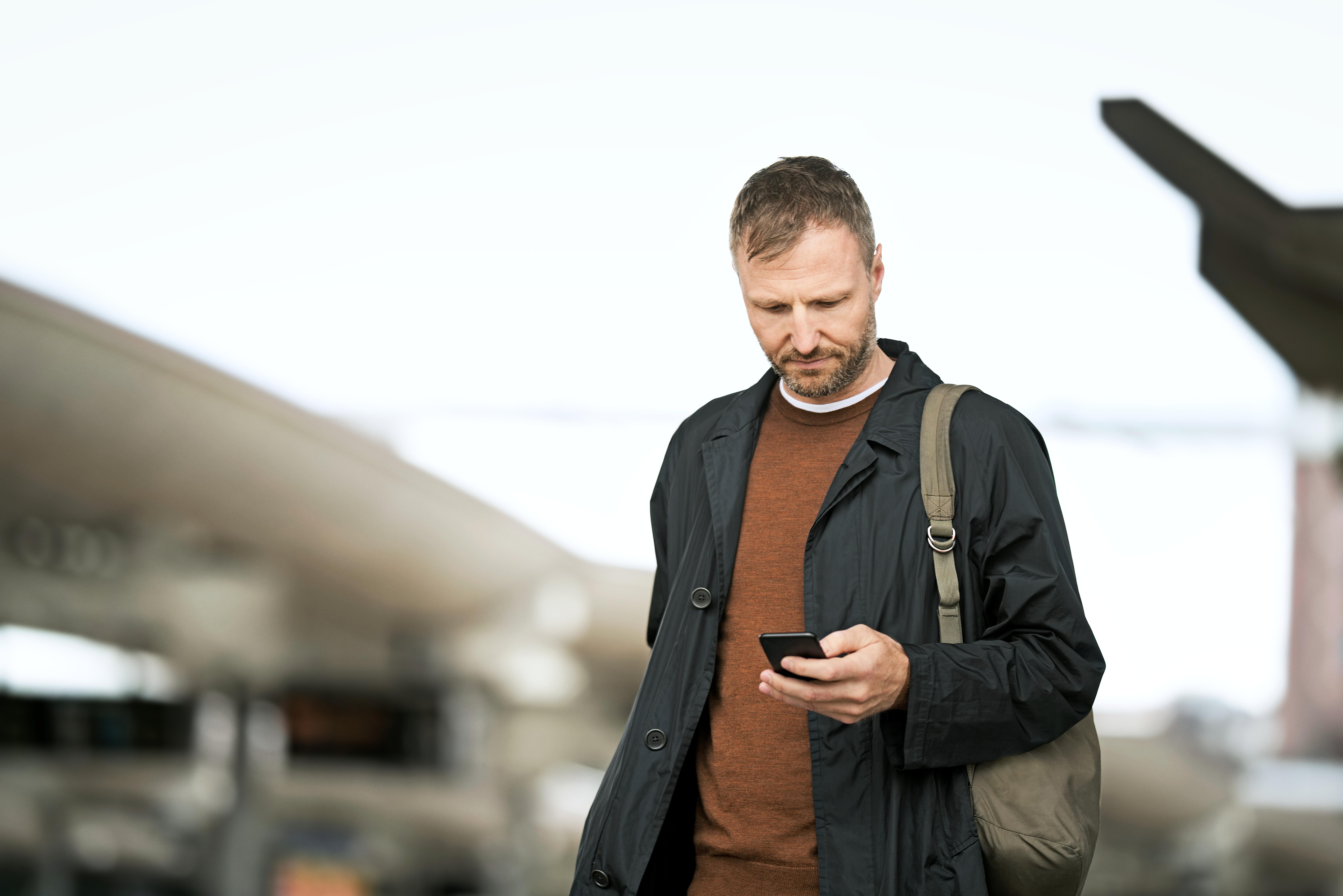 Mann på plattform med mobil i hånda