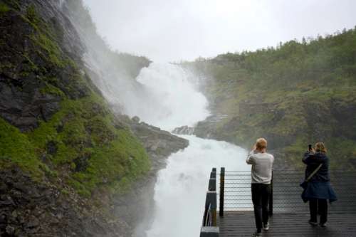 Turister tar bilde av Kjosfossen under reise med Flåmsbana