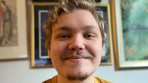 Bilde av Simen, i bakgrunnen henger det bilder på en vegg.