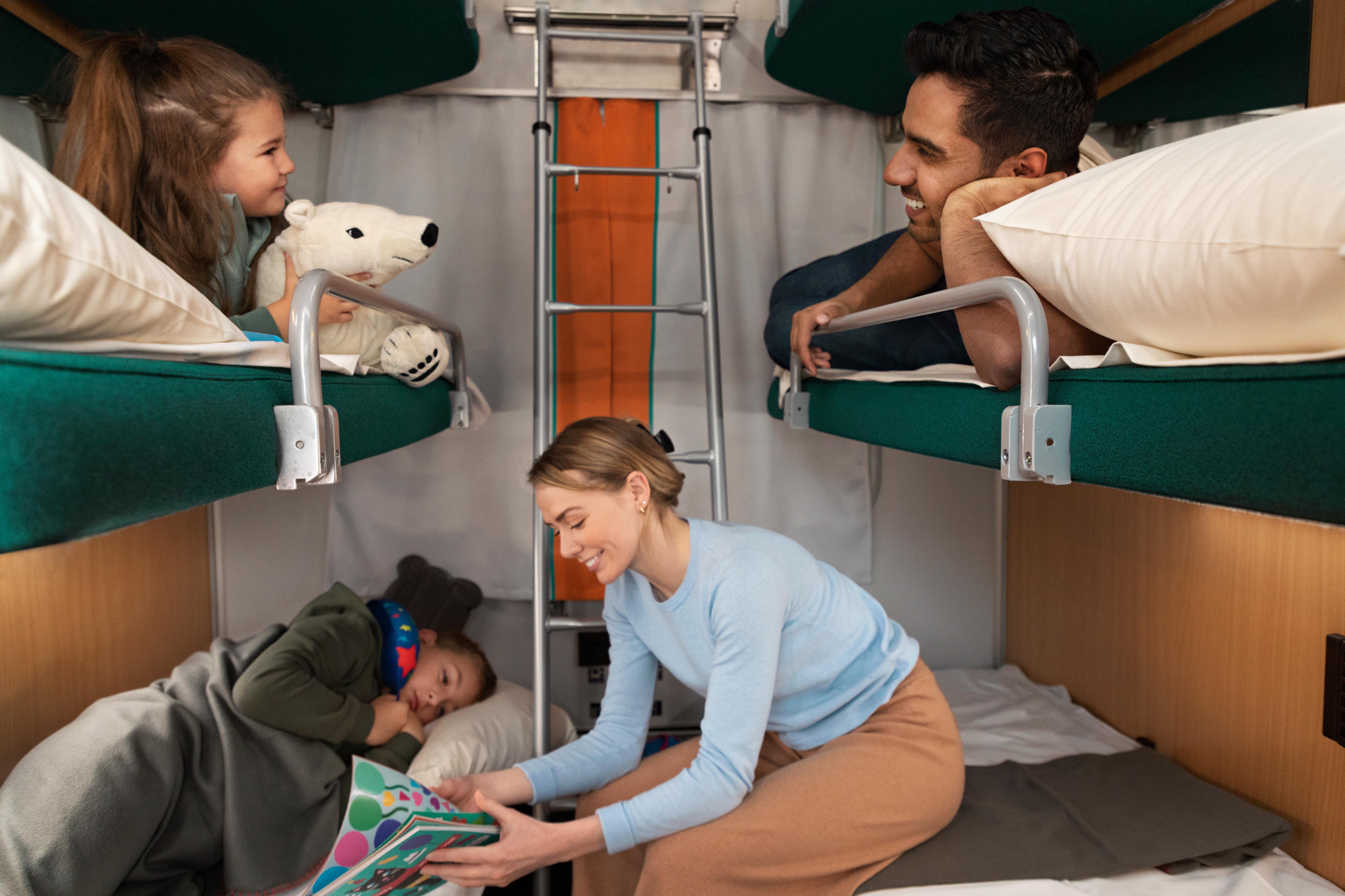 4 personer i en Hvilekupé, en mann og et barn i overkøyer, og et barn en dame i underkøyene.