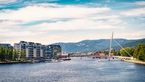 Drammenselva med boligblokker på venstre side og trær til høyre.
