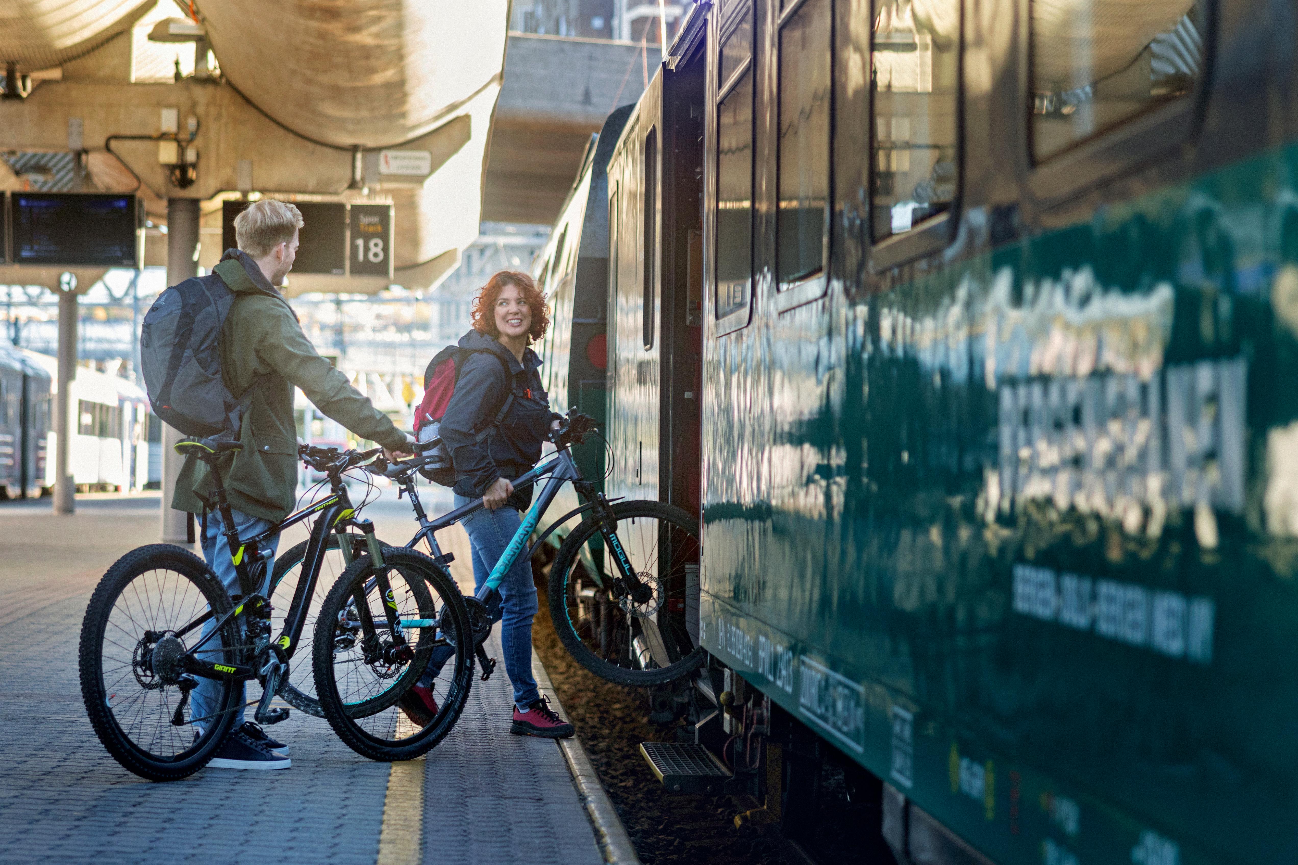 Man and woman load their bicycle onto the train on the Bergen Line