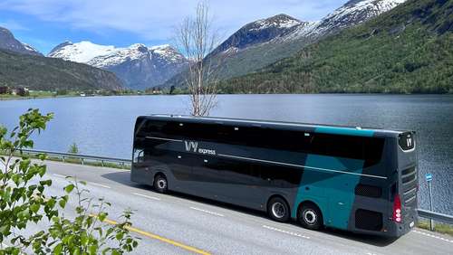 En dobbeldekker som står parkert langs fjord og fjell.